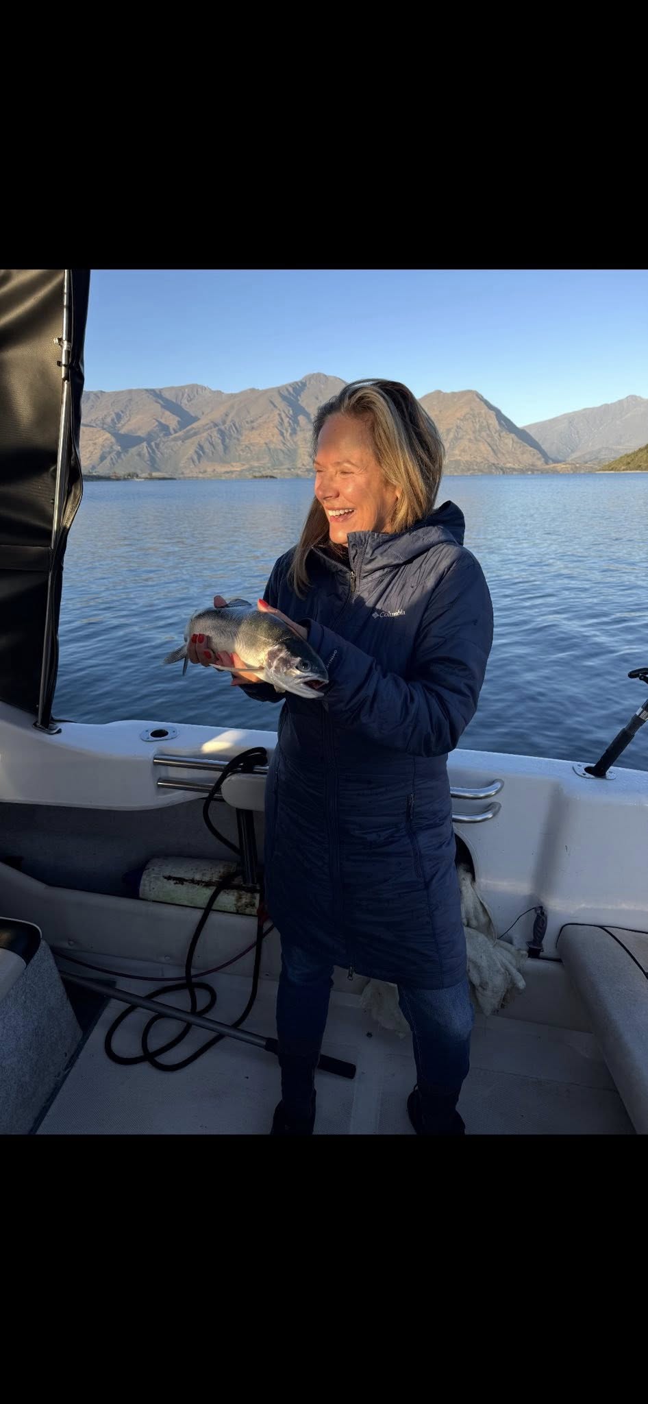 Guest laughing while holding a fish, golden light on Lake Wanaka